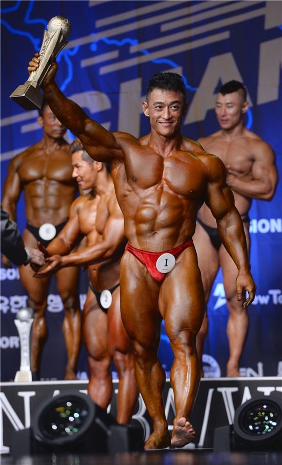 트로피를 들어 올린 우승 선수와 무대 위 선수들